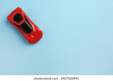 One red car on light blue background, top view with space for text. Children`s toy
