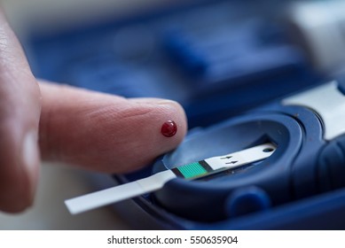 One red drop of blood on the finger ready to measure sugar level