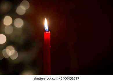 One red melting wax candle burning in front of blurred bokeh Christmas lights - Powered by Shutterstock