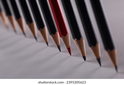 One red pencil is set of identical black counterparts. Uniqueness of business ideas and creative creative approach - Shutterstock ID 2395305623