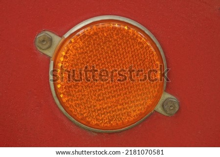 one red round plastic reflector on the metal wall of the trailer