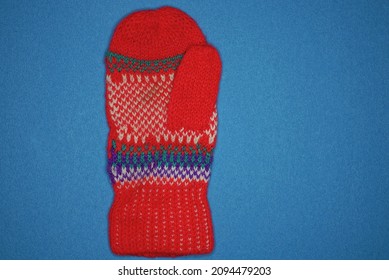 One Red Winter Woolen Mitten With A Pattern Lies On A Blue Table