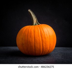 One ripe beautiful pumpkin on black background 