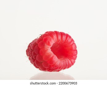 One Ripe Red Raspberry On A White Background. Minimalism. Vitamins, Antioxidants, Healthy Vegetarian Food, Dessert. There Are No People In The Photo. There Is Free Space To Insert.