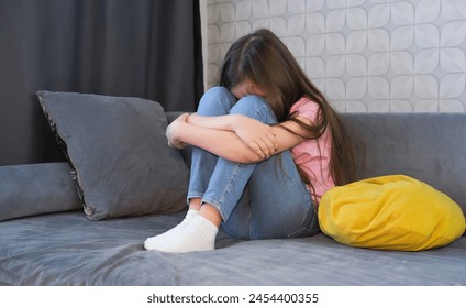 One sad girl sits in anxiety and despair on sofa at home. Concept of bullying, depressive stress or disappointment, sadness. Child abuse. - Powered by Shutterstock