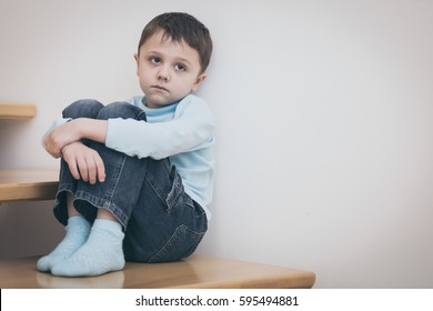 one sad little boy sitting on the stairs in house at the day time. Concept of sorrow. - Powered by Shutterstock