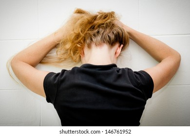 one sad woman sitting on the floor near a wall and holding her head in her hands