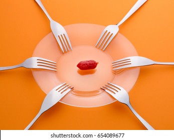 One Sausage And Six Forks. Sharing, Limited Resources, Shortage And Contention Concept. On Orange Background
