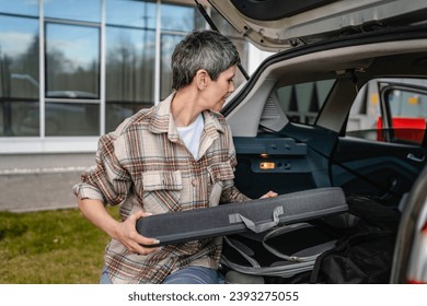 One senior beautiful woman travel concept female take luggage baggage suitcase and other stuff and belongings from the back of her car while moving or arrive to destination real people copy space - Powered by Shutterstock