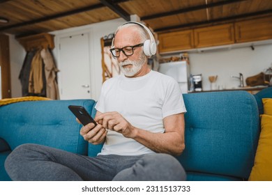 one senior man with headphones use smsrtphone to play music at home - Powered by Shutterstock