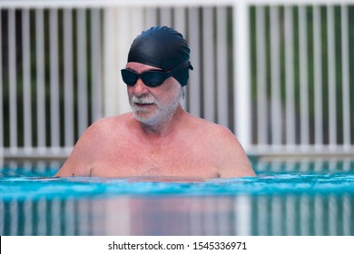 one senior at the pool training alone to be healthy at the morning or afternoon - active mature man swimming with goggles in blue water - Powered by Shutterstock