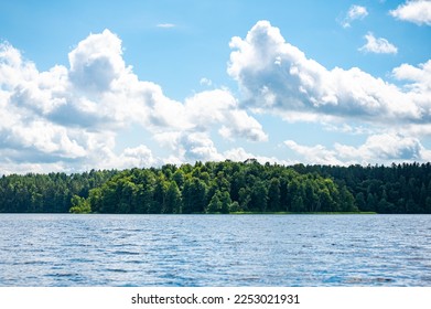 One of several small islands on Asveja the longest lake in Lithuania. Bulrush plants growing on the coast of Asveja lake surrounded by forest. Summer season waterscape scenery landscape. - Shutterstock ID 2253021931