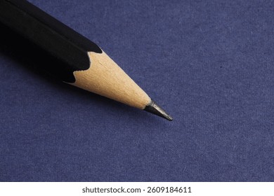 One sharp graphite pencil on blue background, closeup. Space for text