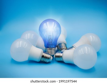 one shining blue light bulb among many LED white light bulb on blue background , idea and creativity concept