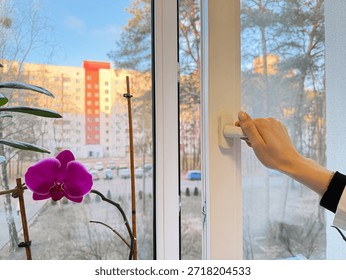 One sided open window. A hand opens a vinyl plastic window