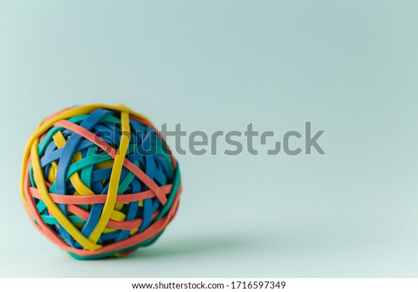 One single multicolored rubber band ball on a
green background