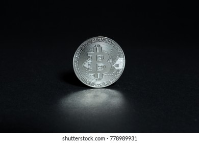One single silver bitcoin on dark black background with copy text space area