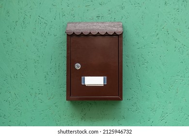 One Single Simple Locked Apartment Letterbox With An Empty Blank Name Tag, Classic Traditional Residence Mailbox Hanging On A Green Wall, Metal Mail Letter Box Front View, Object Closeup, Nobody