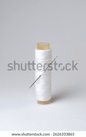 One single thread spool with needle on white background