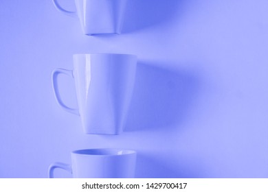 One Singled Out Monochromatic Blue Coffee Mug Lined Up In A Row On Blue Background With Blank Empty Room Space For Text, Copy, Or Copyspace. Modern Top View Concept With Solid Background Backdrop