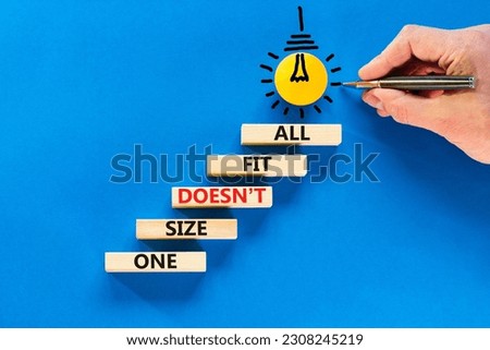 One size does not fit all symbol. Concept words One size does not fit all on wooden blocks. Businessman hand. Beautiful blue background. One size does not fit all business concept. Copy space.