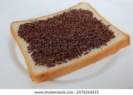 One slice of white square bread, with chocolate sprinkles spread, on white plate, isolated on white background