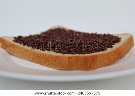 One slice of white square bread, with chocolate sprinkles spread, on white plate, isolated on white background