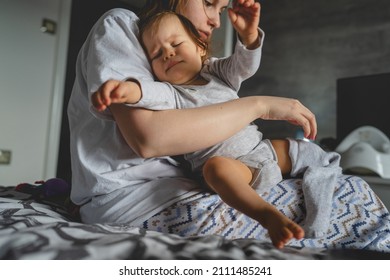 One Small Caucasian Baby Girl And Her Mother Morning Routine Getting Dressed Woman Having Hard Time Trouble While Putting On Clothes On Her Nine Months Old Daughter Real People Family Copy Space