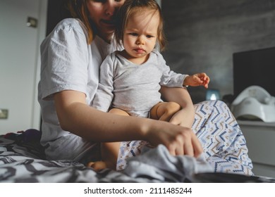 One Small Caucasian Baby Girl And Her Mother Morning Routine Getting Dressed Woman Putting On Clothes On Her Nine Months Old Daughter At Home In Bedroom Real People Family Copy Space