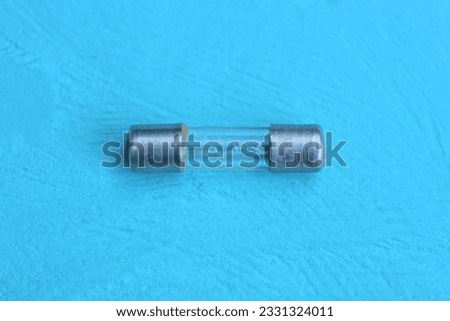 one small electric gray glass metal fuse lies lies on a blue wooden table 商業照片 © 