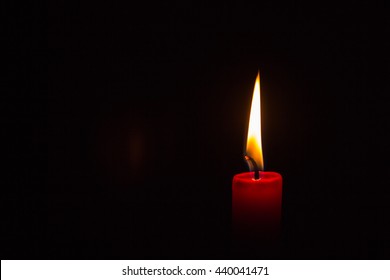 One small lit red candle on a black background - Powered by Shutterstock