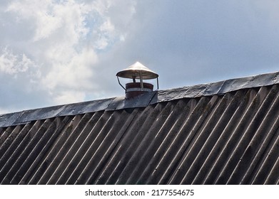 One Small Metal Pipe On A Gray Slate Roof Against A Blue Sky