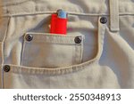 one small plastic modern iron round dangerous wheel red gas lighter lies in the side pocket with rivets of stylish gray denim fashion pants at the smoker