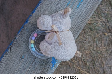 One Small White Plush Toy Dog Lies On A Gray Wooden Table Outdoors