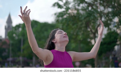 One spiritual young woman standing outdoors raising arms to sky feeling HOPE and FAITH. A joyful person looking UP feeling GRATITUDE - Shutterstock ID 2311186855