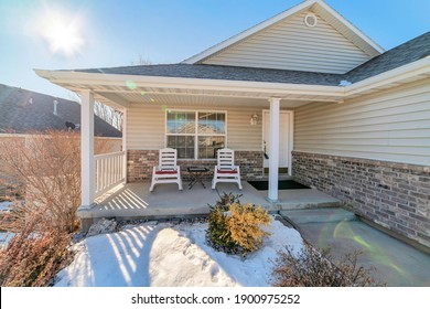 One Storey House With Porch Against Blue Sky And Sun On A Snowy Winter Day