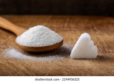 One Sugar Cube In Heart Shape And Wooden Spoon Filled With Sugar On Wood Background