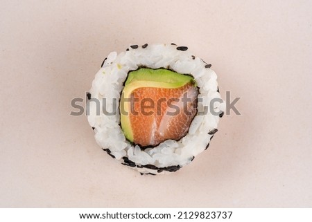 One sushi roll with salmon and avocado and chopsticks on a plate. Japanese dish california roll with fresh fish and rice, close up Stockfoto © 