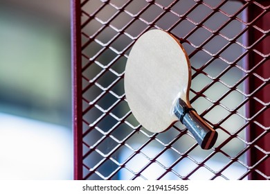 One Table Tennis Paddle Racket Is Hung On Red Grill By A Cable Tie For Display In Exhibition Sports Event