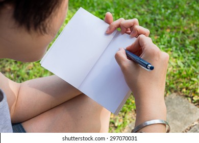 One taking note with book on left hand and pen on right hand
