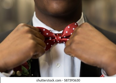 One teen boy adjusts polka dotted red bow tie. Getting dressed and ready for formal high school prom dance. - Powered by Shutterstock