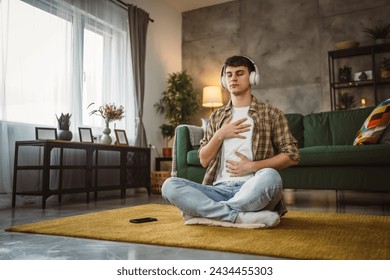 One teen man doing guided meditation yoga self care practice at home - Powered by Shutterstock