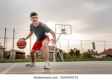 One teenager caucasian male caucasian young man stand on basketball court with ball in the evening ready to play game copy space real person - Powered by Shutterstock