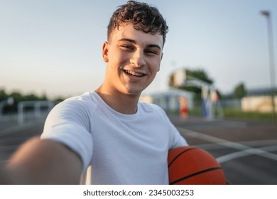 One teenager caucasian male caucasian young man stand on basketball court with ball in the evening ready to play game copy space real person - Powered by Shutterstock