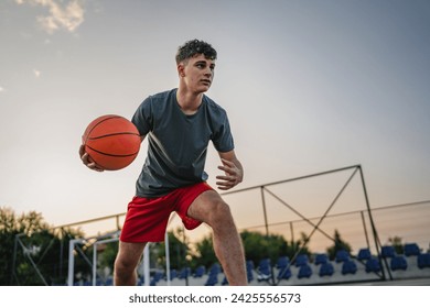 One teenager caucasian male caucasian young man stand on basketball court with ball in the evening ready to play game copy space real person - Powered by Shutterstock