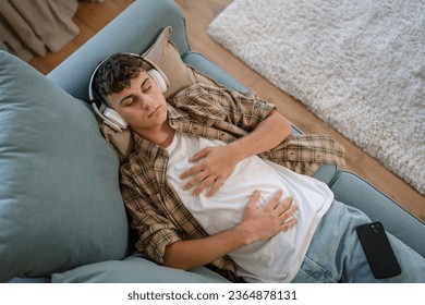 one teenager man young caucasian male use headphones for online guided meditation practice mindfulness yoga with eyes closed at home real people self care manifestation concept copy space generation Z - Shutterstock ID 2364878131