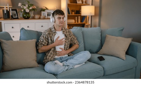 one teenager man young caucasian male use headphones for online guided meditation practice mindfulness yoga with eyes closed at home real people self care manifestation concept copy space generation Z - Shutterstock ID 2364878135