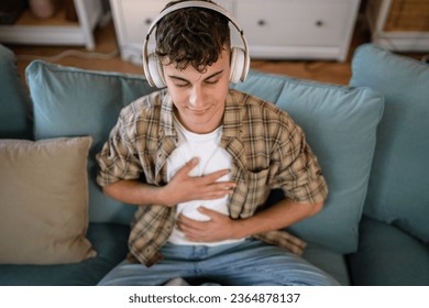 one teenager man young caucasian male use headphones for online guided meditation practice mindfulness yoga with eyes closed at home real people self care manifestation concept copy space generation Z - Shutterstock ID 2364878137