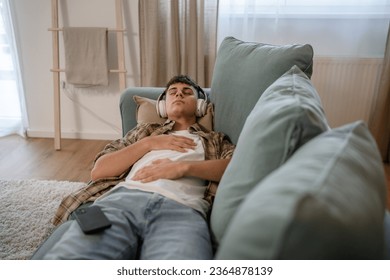one teenager man young caucasian male use headphones for online guided meditation practice mindfulness yoga with eyes closed at home real people self care manifestation concept copy space generation Z - Shutterstock ID 2364878139