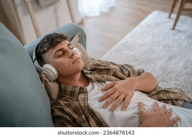 one teenager man young caucasian male use headphones for online guided meditation practice mindfulness yoga with eyes closed at home real people self care manifestation concept copy space generation Z - Shutterstock ID 2364878143